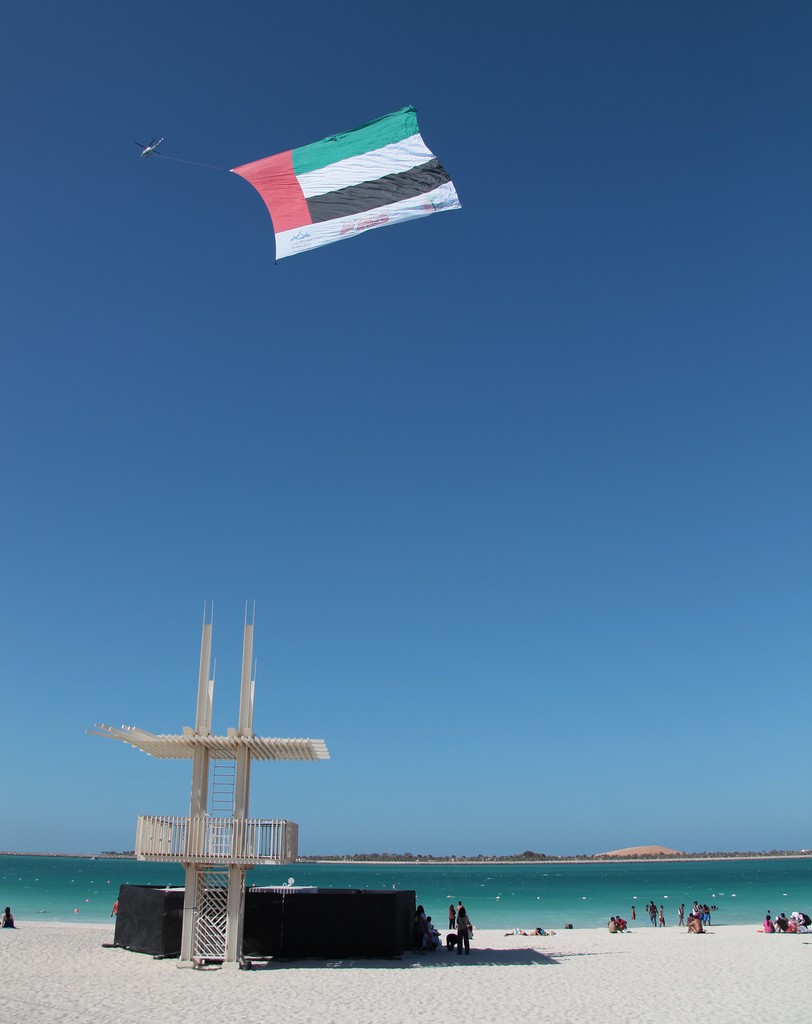 Abu Dhabi public beach National day United Arab Emirates flag towing by Falcon Aviation Services Bell 412 Helicopter
