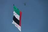 Bell 412 helicopter towing the world’s largest aerial banner United Arab Emirates flag above Abu Dhabi Corniche